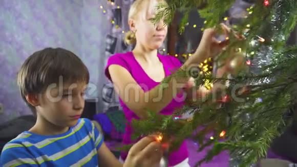 母亲和孩子用挂球和花环装饰圣诞树视频的预览图