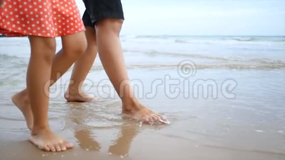 慢动作亚洲小女孩和妈妈一起在沙滩上与自然海浪海岸散步为暑假提供概念视频的预览图