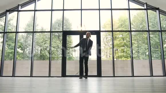 穿着灰色西装的年轻商人正在跳舞抛出文件在办公室的商业成就视频的预览图