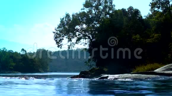 蓝色的河流与树木的轮廓和远处的树林相映成趣视频的预览图