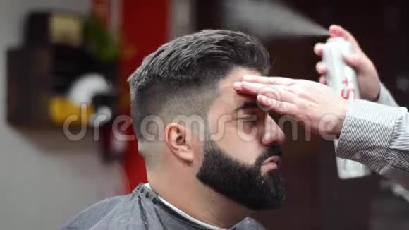 理发师在理发店用喷发固定发型视频的预览图