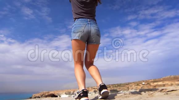快乐的女人在海边的岩石悬崖上跳跃快乐的女孩享受假期视频的预览图