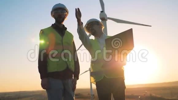 日落景观与两名工程师交谈旁边的一套涡轮塔可再生替代能源环境视频的预览图