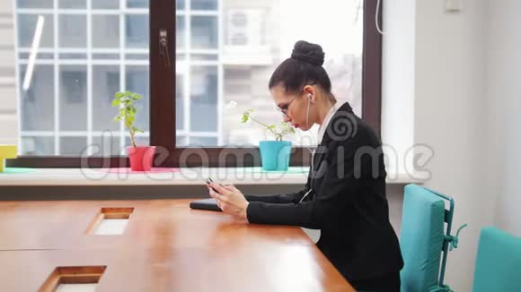 商业概念一个戴着耳机的女人在玩手机视频的预览图