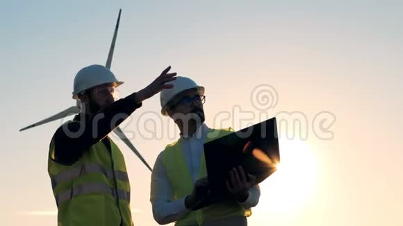 两名工程师正在阳光下在一台风力涡轮机前交谈清洁环保的能源理念视频的预览图
