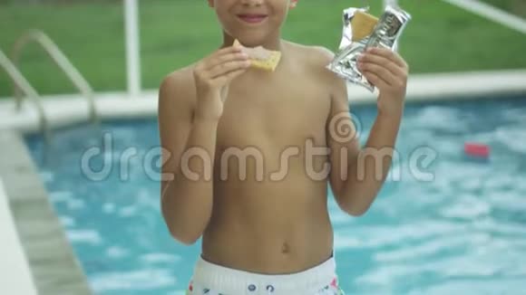 一个可爱的男孩在游泳池前吃饭和微笑的慢动作视频的预览图