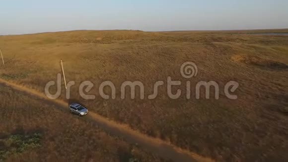 正面鸟瞰大型银色越野车在乡间小路上的草原上行驶视频的预览图