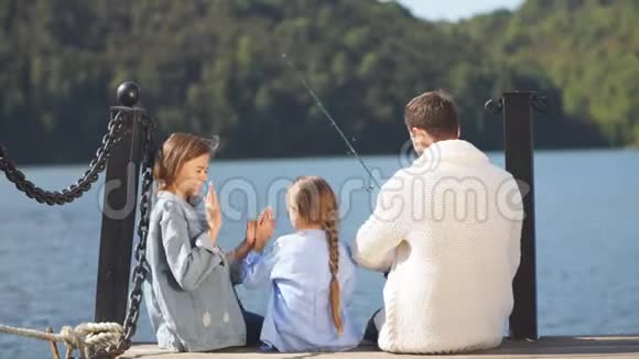 家人在秋日坐在码头上秋天的家庭肖像视频的预览图