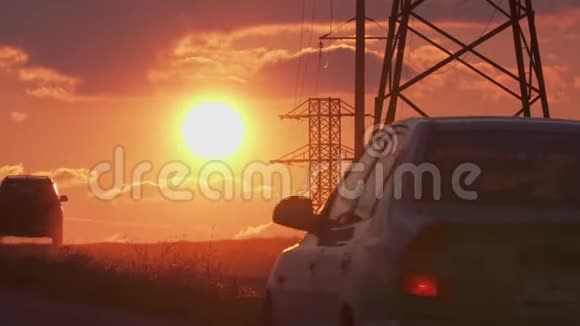 高压电力支持橙色日落和汽车上路视频的预览图
