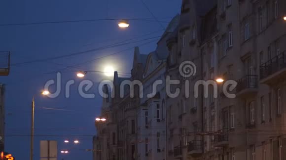 明亮的满月在城市街道上可以看到使用电视镜头城市灯光在前景和里加的典型视频的预览图