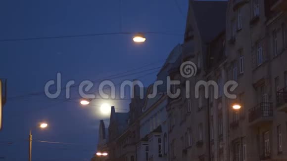 明亮的满月在城市街道上可以看到使用电视镜头城市灯光在前景和里加的典型视频的预览图
