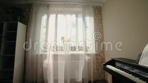 风中吹着的白色窗帘花瓶里的向日葵房间里的钢琴视频的预览图