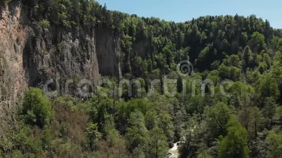 在一个有高崖密林和河流的深岩石峡上观看相机飞行的空中景色视频的预览图