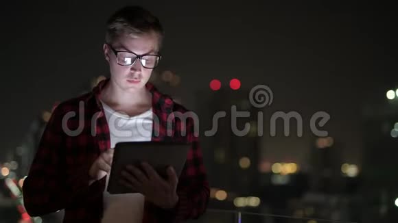 快乐潮人思考与数字平板电脑在夜景中的应用视频的预览图