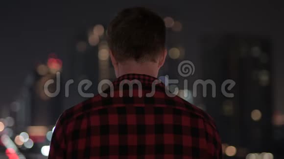 年轻的嬉皮士看城市夜景的后景视频的预览图