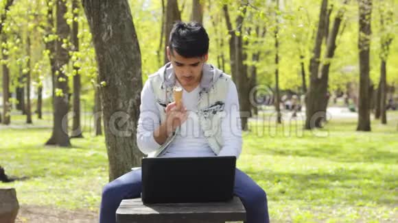 快乐男人自由职业者在笔记本电脑上工作吃冰淇淋视频的预览图