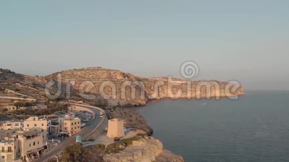 海天对峙的岩石海岸上有酒店和交通道路的旅游城镇鸟瞰视频的预览图