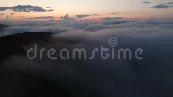 日落后在蓝色的小时低键鸟瞰傍晚飞越云层和山上的概念视频的预览图