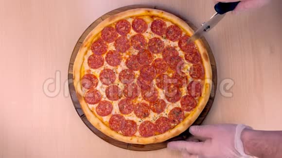 厨师在切片上切腊肠披萨手在橡胶手套特写顶部视图视频的预览图