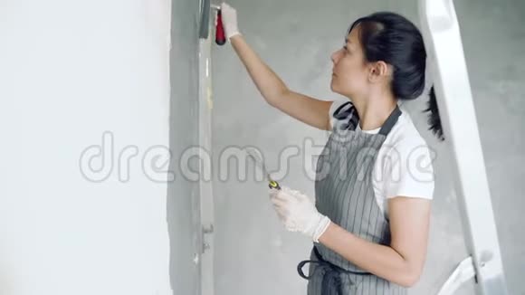 女工人在公寓或房子里用铲子粉刷墙壁视频的预览图