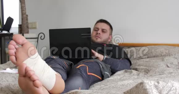 一个腿受伤的蓄胡子男人用笔记本电脑完成任务开始在卧室里思考视频的预览图
