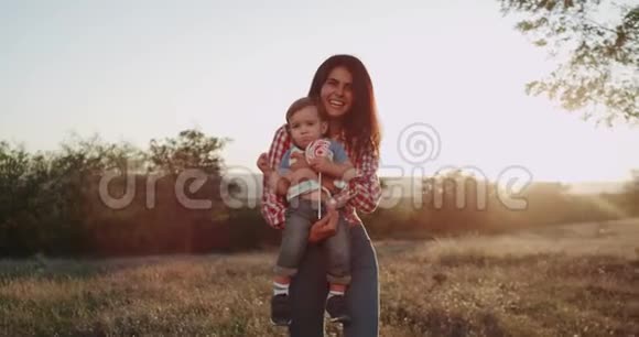在镜头前一位年轻的微笑的母亲和她的孩子男孩一岁互相拥抱宝贝吃了一大块视频的预览图