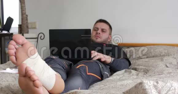 一个腿受伤的蓄胡子男人用笔记本电脑完成任务开始在卧室里思考视频的预览图