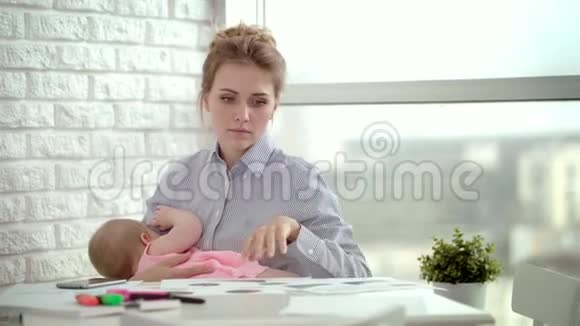工作母亲手里拿着熟睡的婴儿厌倦了妈妈工作的文件视频的预览图