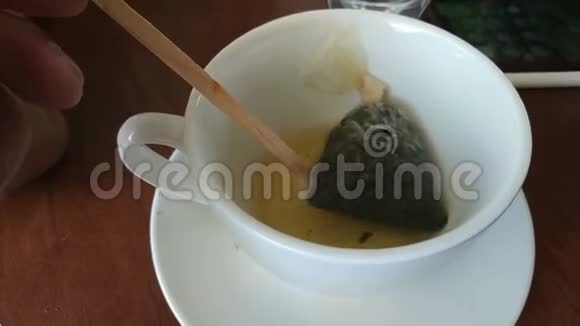用搅拌棒将茶袋放入桌上的杯子中视频的预览图