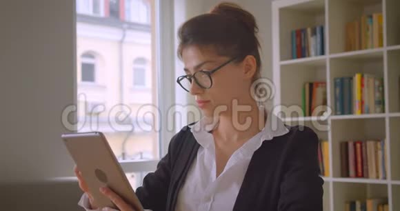 年轻漂亮的高加索女商人戴着眼镜用平板电脑拍摄特写镜头并在镜头中显示绿色屏幕视频的预览图