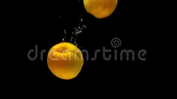 成熟的杏子在黑色的背景下落入透明的水中视频的预览图