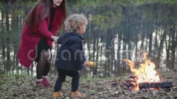 妈妈和小儿子在秋湖附近的篝火旁散步视频的预览图