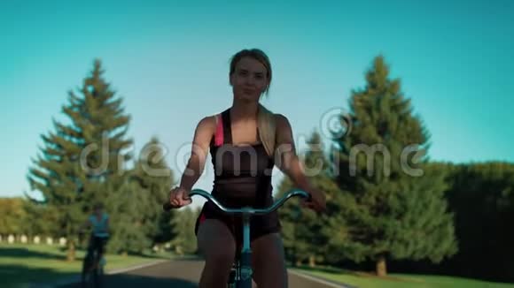健身妇女骑自行车在城市公园夏天年轻女子自行车视频的预览图
