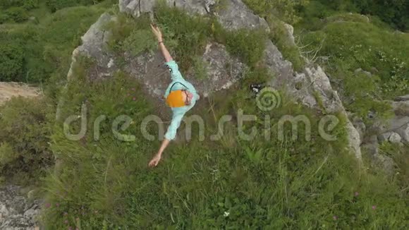 空中俯瞰着一个女孩手臂伸出站在大自然的岩石边缘从上面看视频的预览图