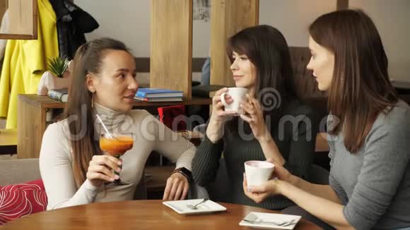 三个女朋友在咖啡馆见面喝饮料互相交谈视频的预览图