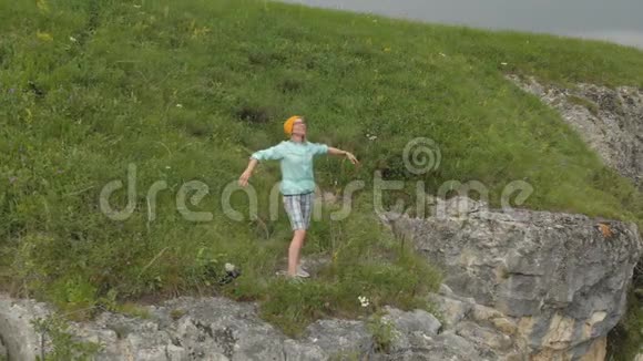 一个女孩伸展到侧面的空中景色站在大自然岩石的边缘视频的预览图