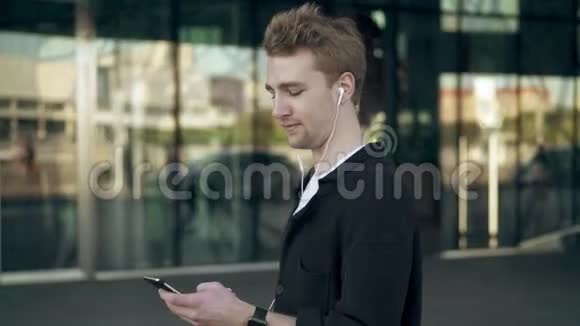 带智能手机和咖啡听音乐的微笑年轻人的侧视视频的预览图