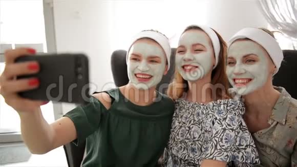 三个年轻快乐的女人带着面具在水疗中心自拍友谊和福利概念健康美视频的预览图