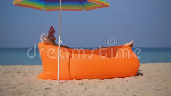一名年轻女子躺在一张充气沙发上的热带海滩上的超慢镜头暑假概念视频的预览图