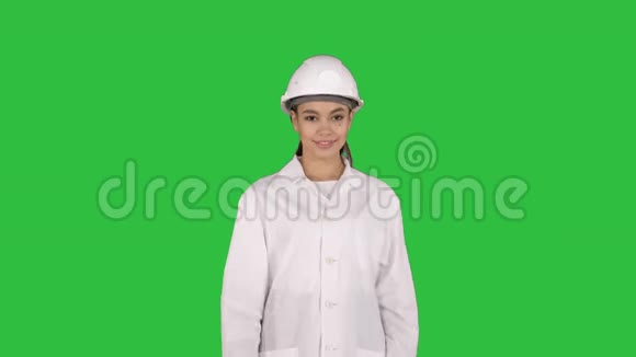 成熟的女工程师戴着安全帽在绿色屏幕上行走时用手向产品或文字表示视频的预览图