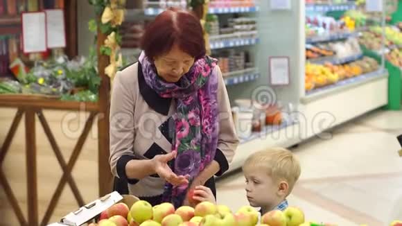 一位老年妇女带着她的小孙子在超市买新鲜苹果视频的预览图