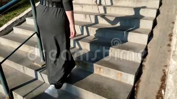 后景一个穿着灰色长裙白色运动鞋的女人走在人行道上上楼梯视频的预览图