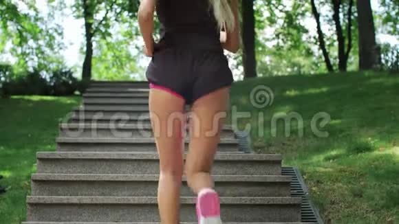 健身妇女在夏季公园晨跑时跑楼梯视频的预览图