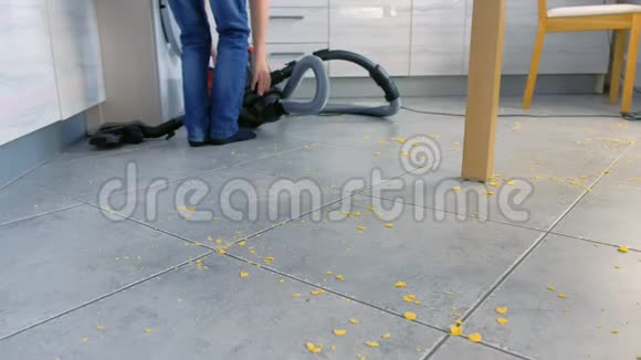 小男孩给厨房地板吸尘他整理了散落在灰色瓷砖上的玉米片腿部特写视频的预览图