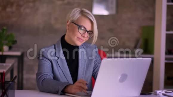 中年短发女商人戴着眼镜在办公室座位上跳舞的肖像视频的预览图