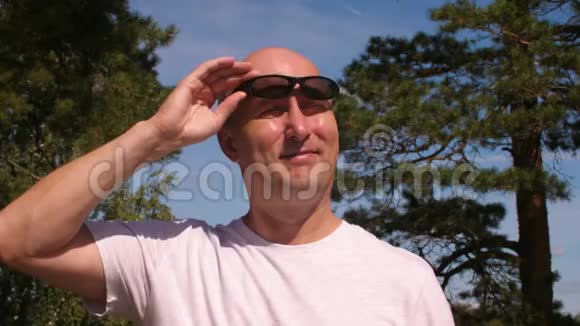 绿色森林中阳光明媚的夏日戴墨镜的成年男子视频的预览图