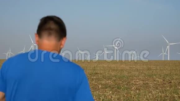 农夫在他的田野上走向风力涡轮机用手机交谈电力生产绿色能源视频的预览图