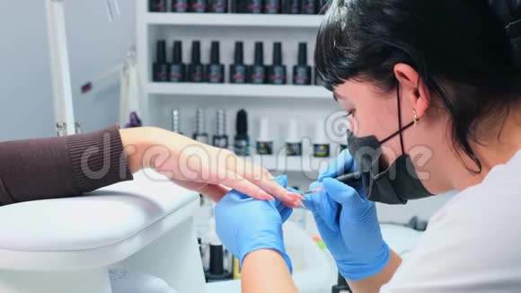 医生正在美容院给顾客的指甲美容院给客户的指甲涂上凝胶抛光剂竖起钉子假人视频的预览图