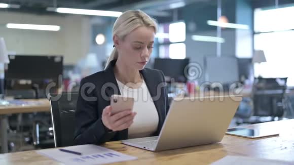 在办公室使用智能手机的开朗的女商人视频的预览图