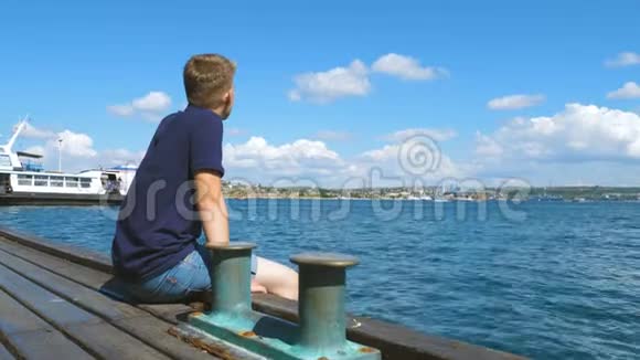 一个年轻人坐在城市海港的码头上视频的预览图